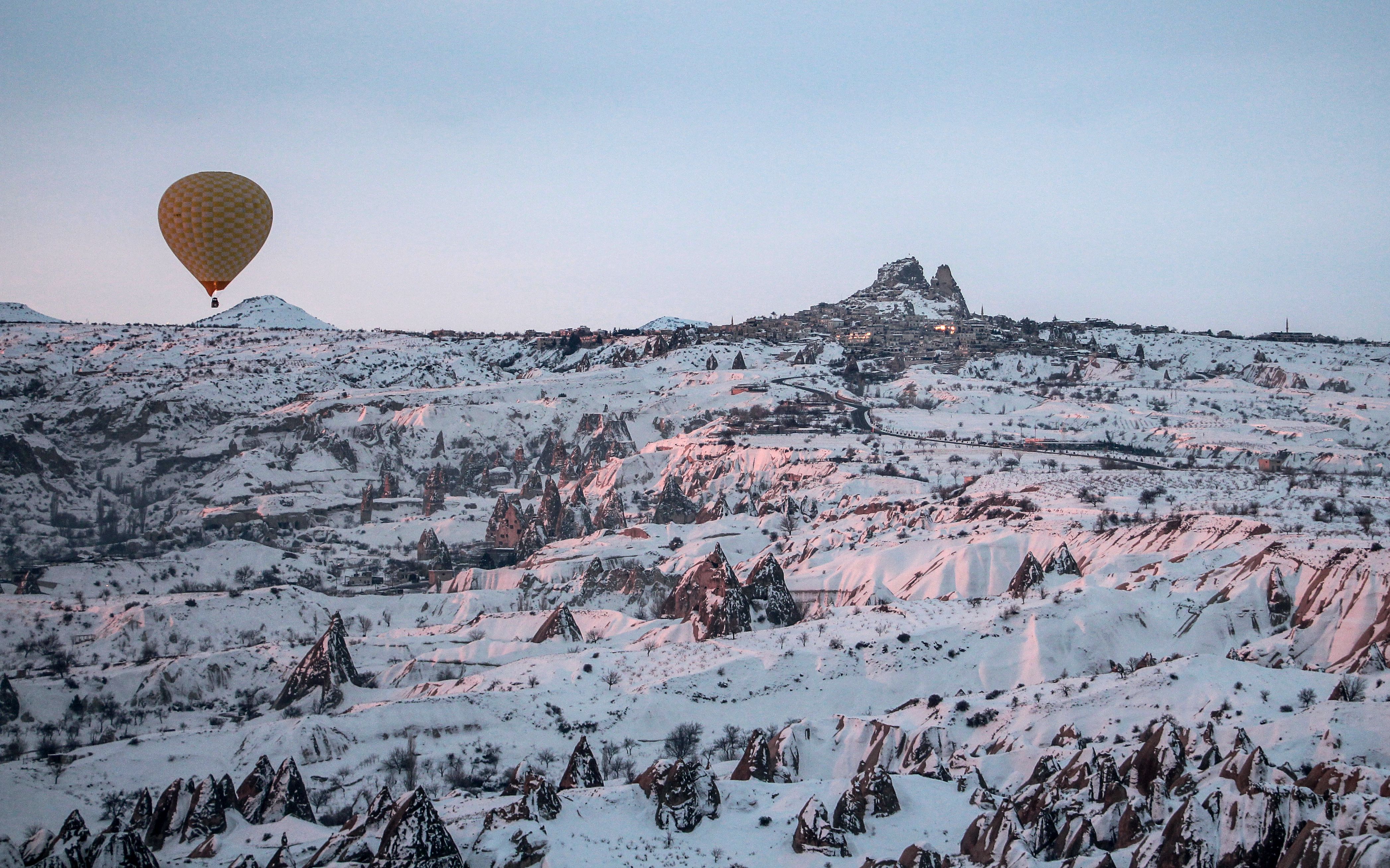 A hot air balloon above snow-covered Cappadocia near Uçhisar
